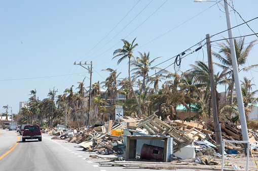 There are mounds of trash and debris placed along side of a roadway after a hurricane hit the Florida Keys. Trees have fallen on power lines causing outages. Shot taken with Canon 5D Mark lV